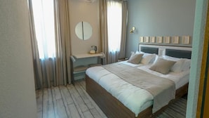 Un dormitorio con cama, mesitas de noche, un espejo y cortinas.