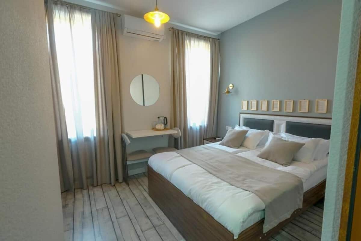 Une chambre à coucher avec un lit, des tables de chevet, un miroir et des rideaux.