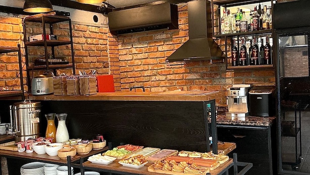 Una cocina rústica con paredes de ladrillo, un horno de leña y una variedad de alimentos a la vista.