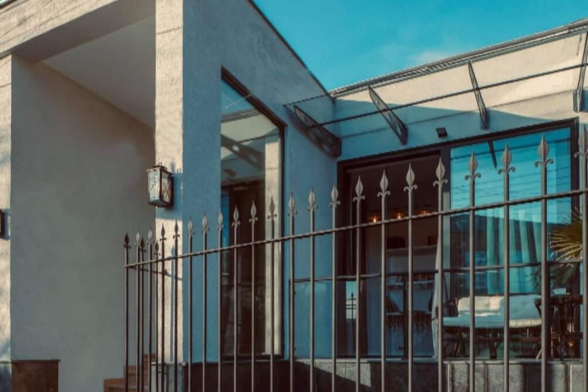 Un bâtiment à la façade blanche, doté de grandes fenêtres et d’une clôture en métal.