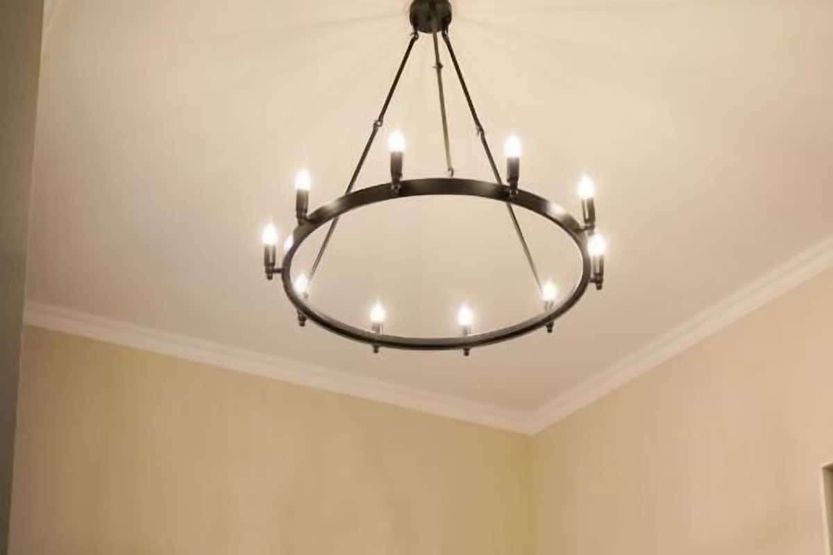 Une chambre à coucher avec un lit, un miroir rond et un lustre.