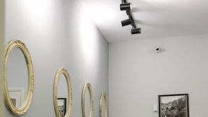 Una sala de estar moderna con un sofá, una mesa de comedor y tres espejos colgados en la pared.