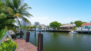 A waterfront dock with boats, a thatched-roof building, and a cityscape in the background. - Waterfront Home Steps to Beach (Fort Lauderdale)