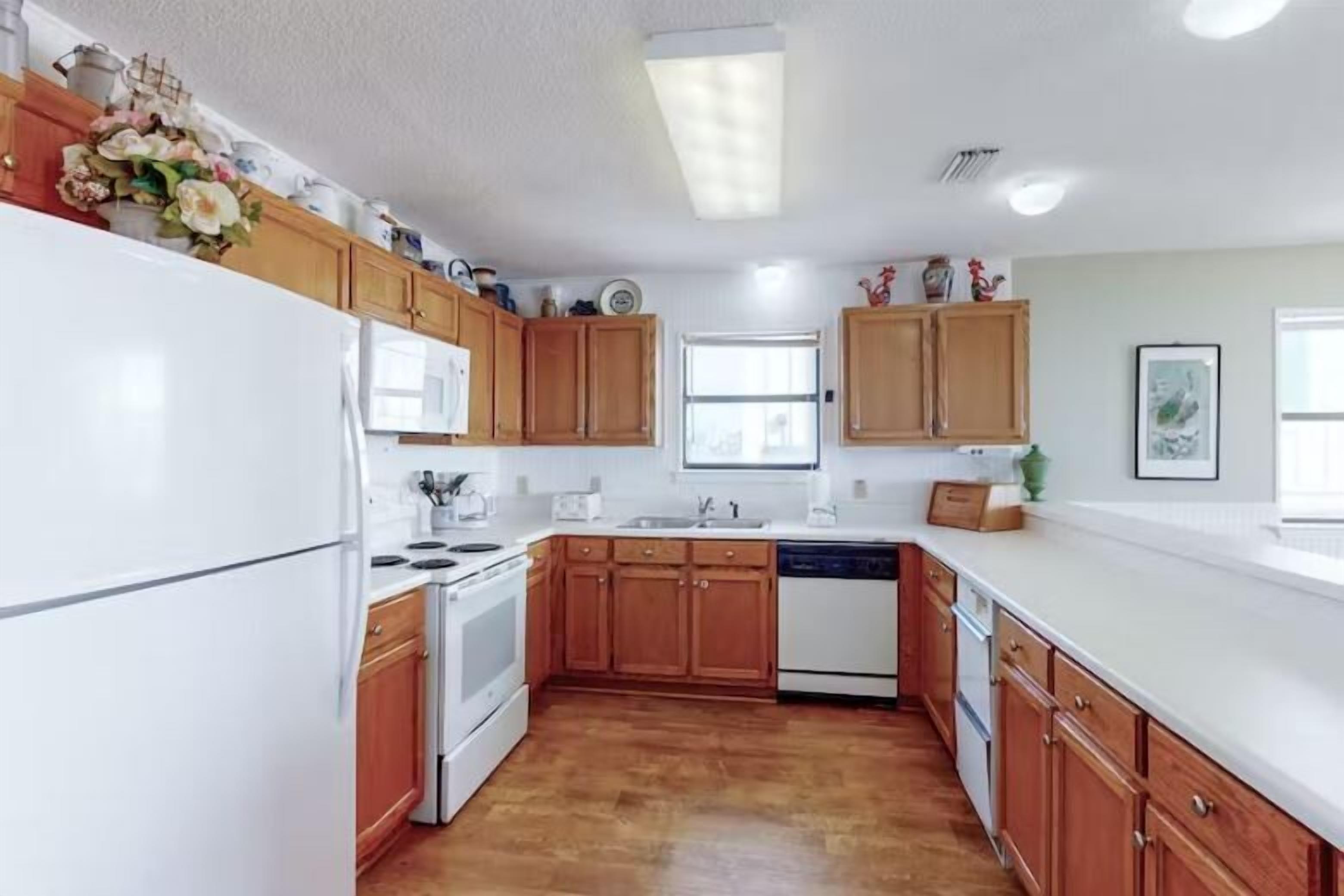 A kitchen with wooden cabinets, white appliances, and a window providing natural light.