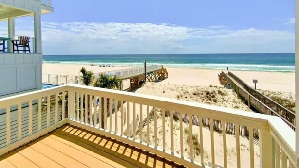A beach view from a balcony with a wooden deck, a sandy beach, and a clear blue sky. - Beachfront - Great Location! (Gulf Shores)