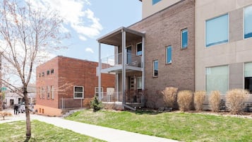 Un bâtiment moderne avec une façade en briques, un espace extérieur couvert et une cour verdoyante.