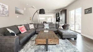 Ein modernes Wohnzimmer mit einer Eckcouch, einem Couchtisch und einem großen Fenster mit Blick auf die Stadt.