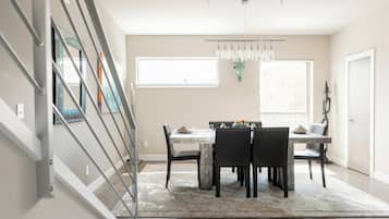 Un coin repas comprenant une table et des chaises, un lustre et une fenêtre.