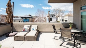 Eine Dachterrasse mit Lounge-Bereich, einem Tisch und Stühlen.
