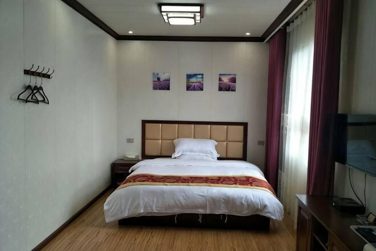 A hotel room with a bed, a nightstand, a TV, and a wall-mounted TV.