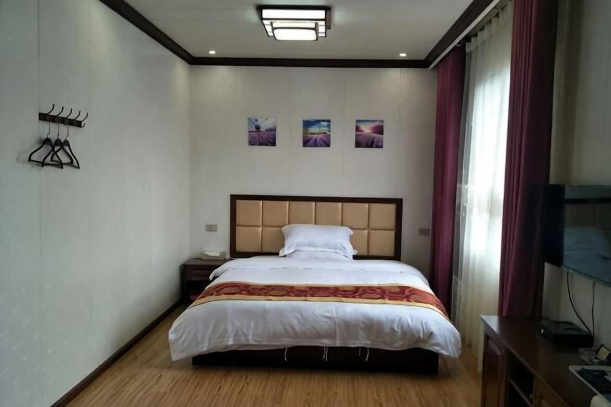 A hotel room with a bed, a nightstand, a TV, and a wall-mounted TV.