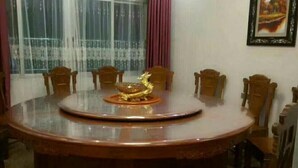 Una mesa de comedor redonda de madera con un centro decorativo dorado, rodeada de sillas de madera.
