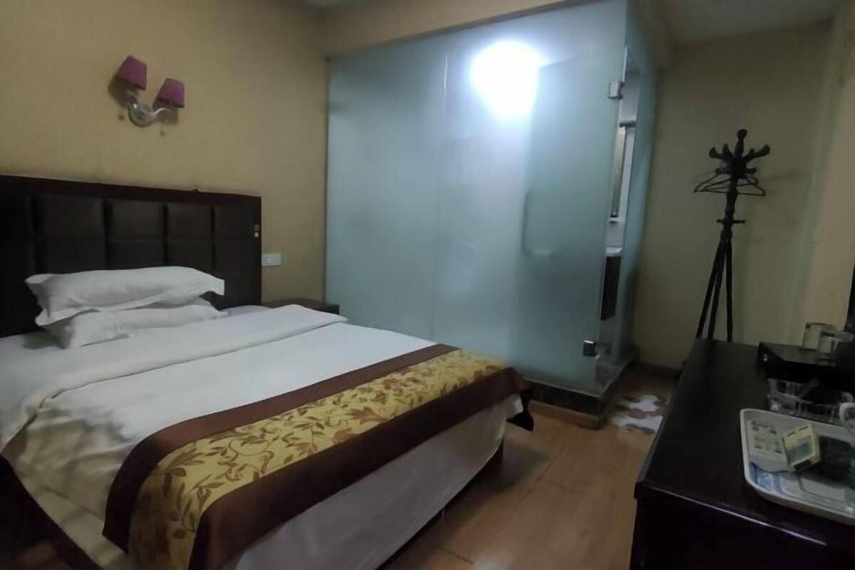 A hotel room with a bed, a desk, a coat rack, and a door.