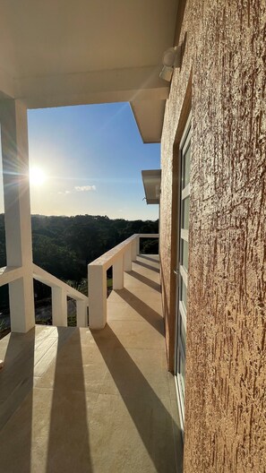 Un balcon donnant sur un paysage vallonné et un ciel dégagé.