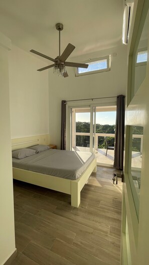 A bedroom with a bed, a ceiling fan, a window, and a view of the outdoors.