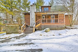 A cabin with a wooden exterior, a porch, and a staircase leading to the entrance.