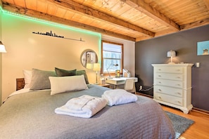 Un dormitorio con cama, almohadas, cómoda, escritorio y ventana.