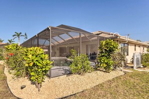 Ein überdachter Außenbereich mit Schwimmbad, umgeben von einem Garten mit verschiedenen Pflanzen und einer Pergola.