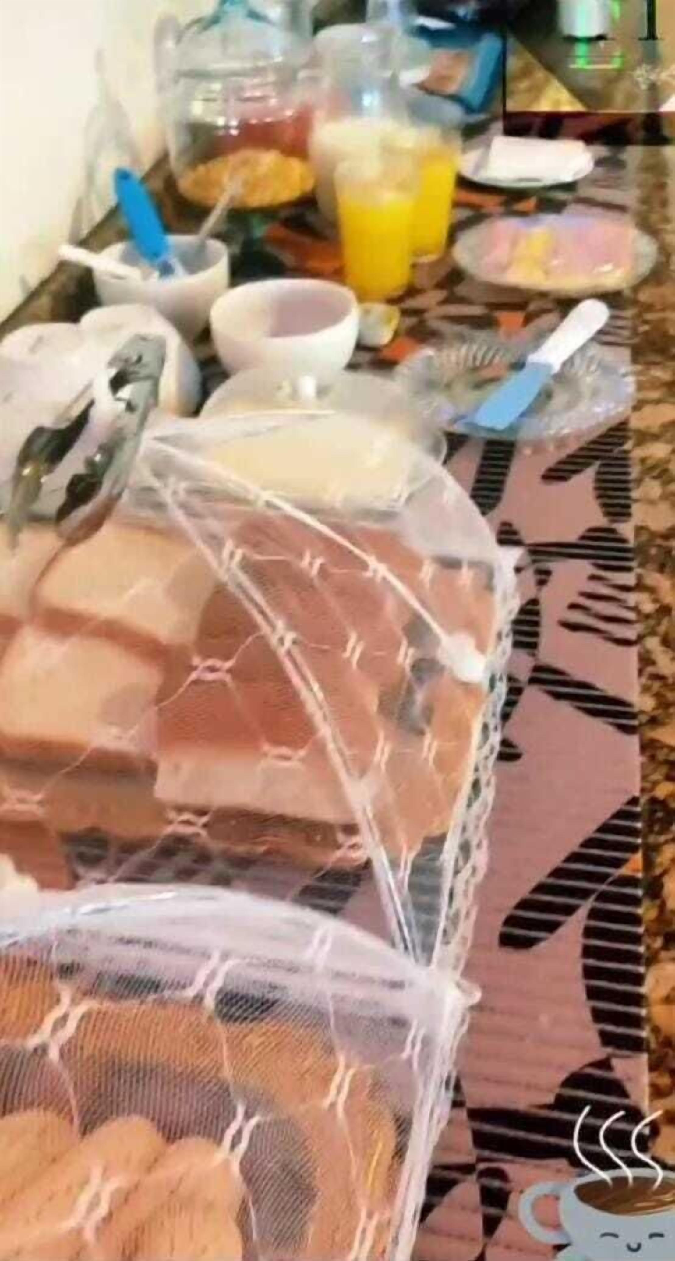 A dining table with various food items and drinks, covered with a protective plastic sheet.