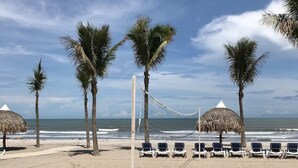 Uma rede de voleibol de praia com palmeiras e cadeiras de praia.