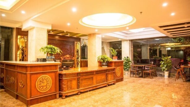A reception area with a wooden reception desk, potted plants, and a seating area with chairs and tables.