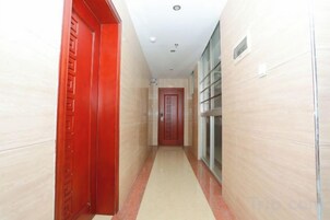Un pasillo con una puerta roja a la izquierda y una puerta de cristal a la derecha.