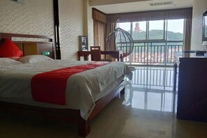 Una camera d'albergo con un letto grande, un balcone con vista e una scrivania con una sedia.