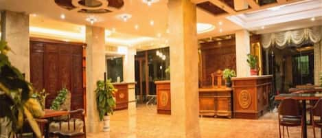 A hotel lobby with a reception desk, seating area, and a large wooden table.