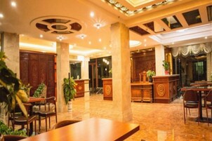 Un vestíbulo de hotel con mostrador de recepción, zona de estar y una gran mesa de madera.