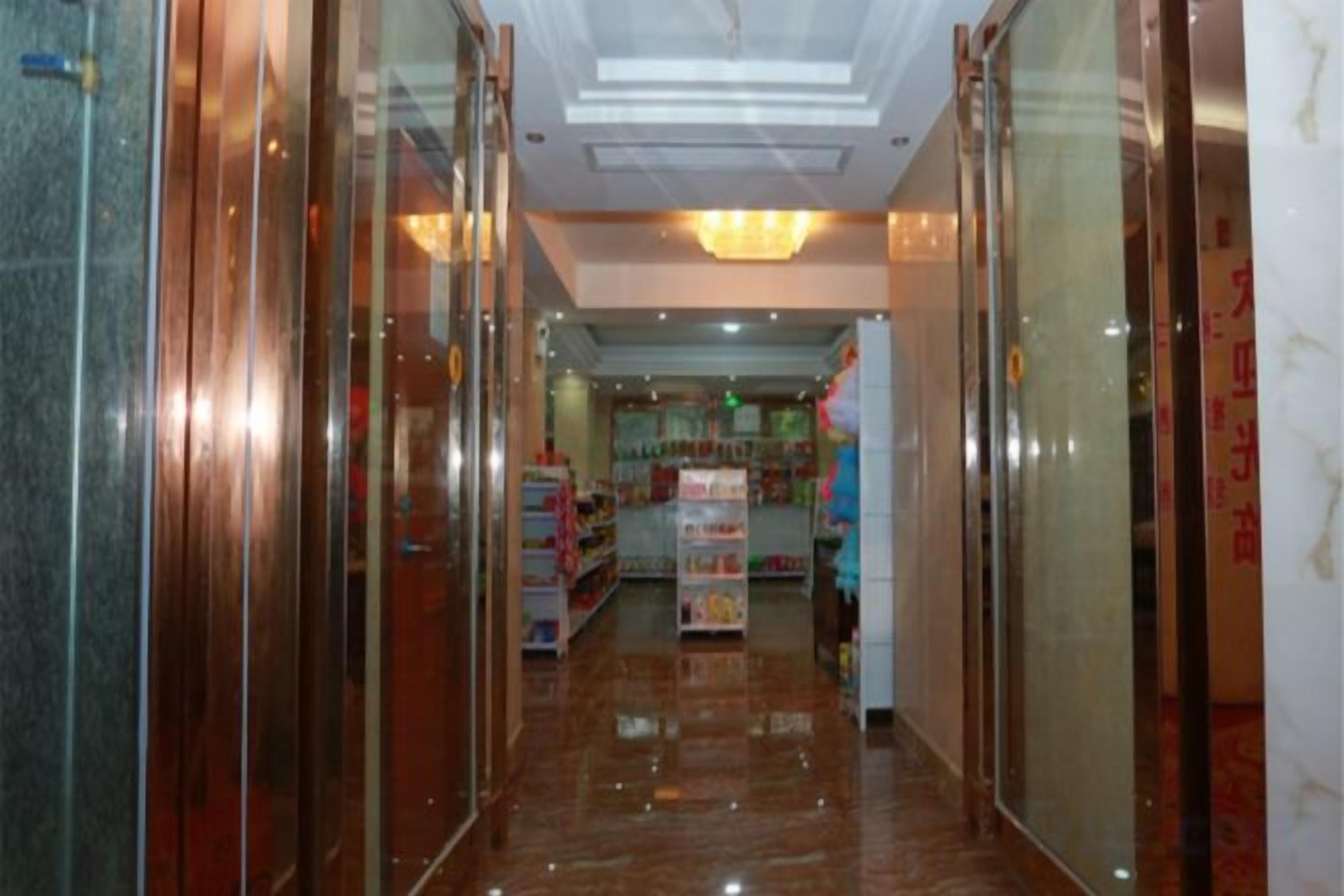 A corridor with glass doors, a ceiling light, and a store in the background.