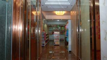 A corridor with glass doors, a ceiling light, and a store in the background.