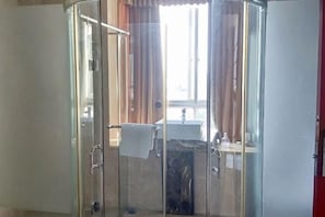 A glass-enclosed shower area with a visible sink and window.