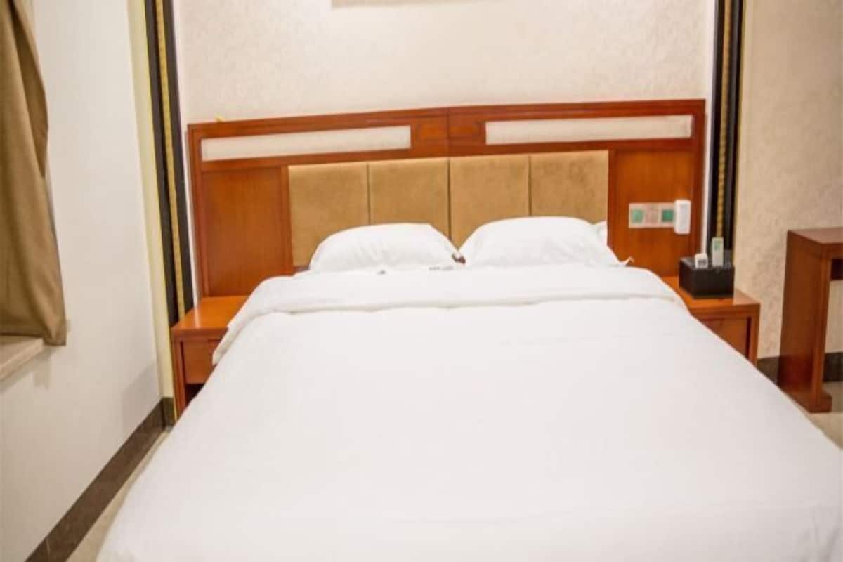Ein Hotelzimmer mit Bett, Holz-Kopfstütze, Nachttischen und einem Beistelltisch.