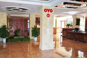 A hotel lobby with a reception desk, a pillar with the hotel name, and potted plants. - Jindiya Hotel (Fangchenggang)