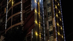 A multi-story building with balconies and a facade adorned with string lights.