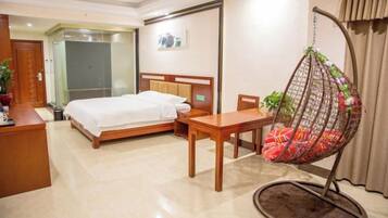 A hotel room with a bed, a desk, a hanging chair, and a door leading to another room.