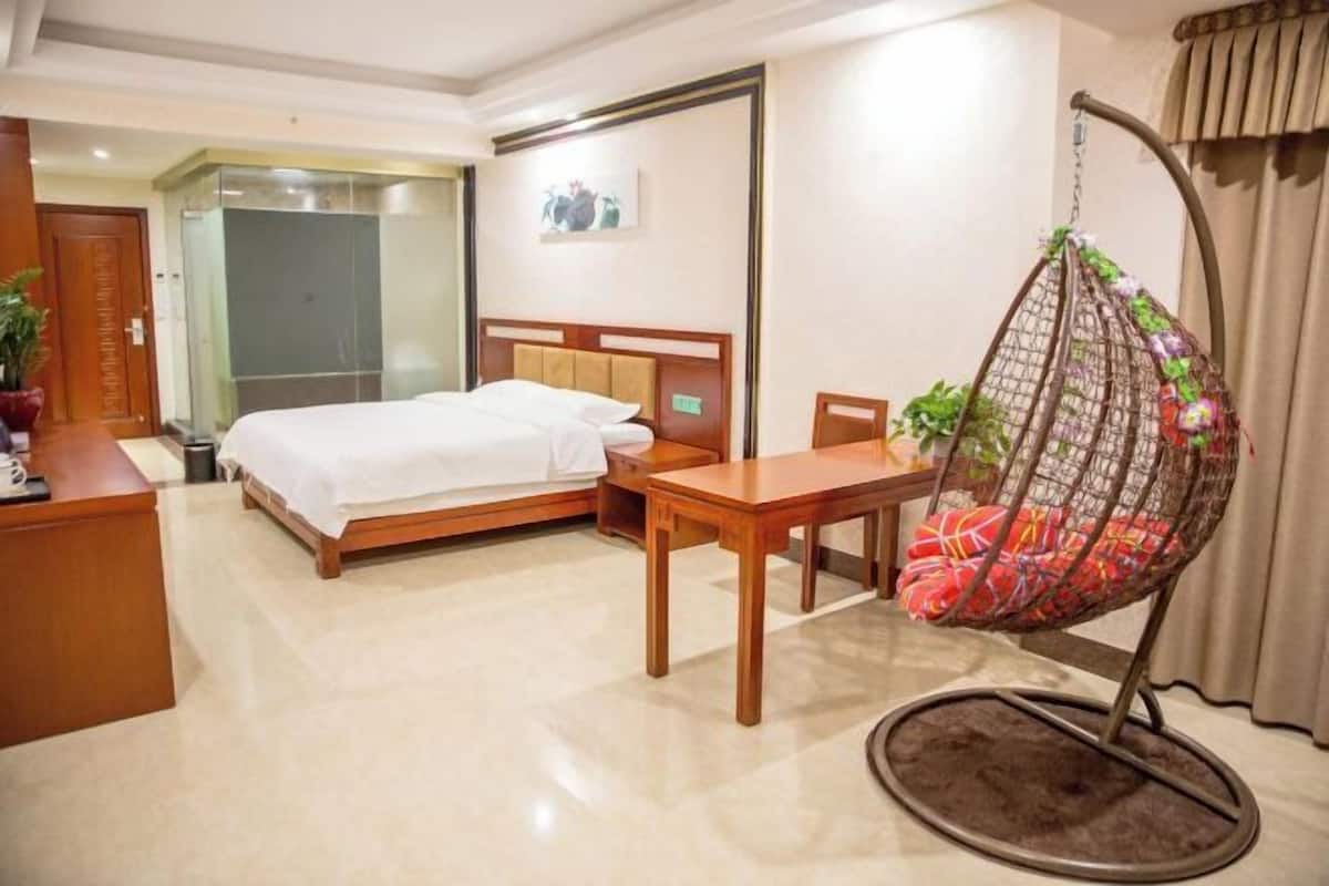 Ein Hotelzimmer mit Bett, Schreibtisch, Stuhl und einer Hängematte.