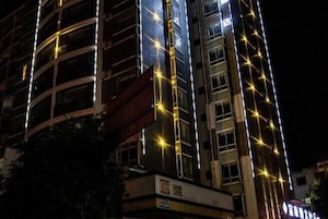 Un edificio de varios pisos con líneas verticales iluminadas y una estructura curva en la base.