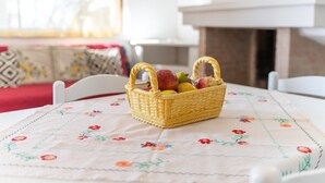 Una cesta de mimbre con frutas sobre una mesa con mantel floreado.