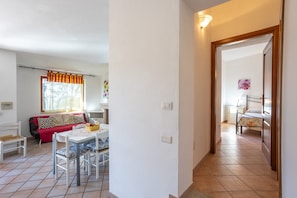 A room with a dining table, chairs, a sofa, and a bed.
