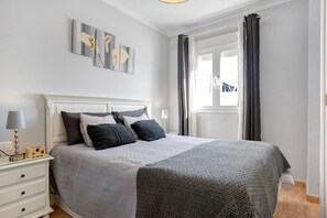 A neatly arranged bedroom with a bed, bedside table, lamp, and artwork on the wall.