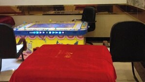 A room with a red table, a colorful arcade machine, and black chairs. - Haiyue Hotel (Ya'an)