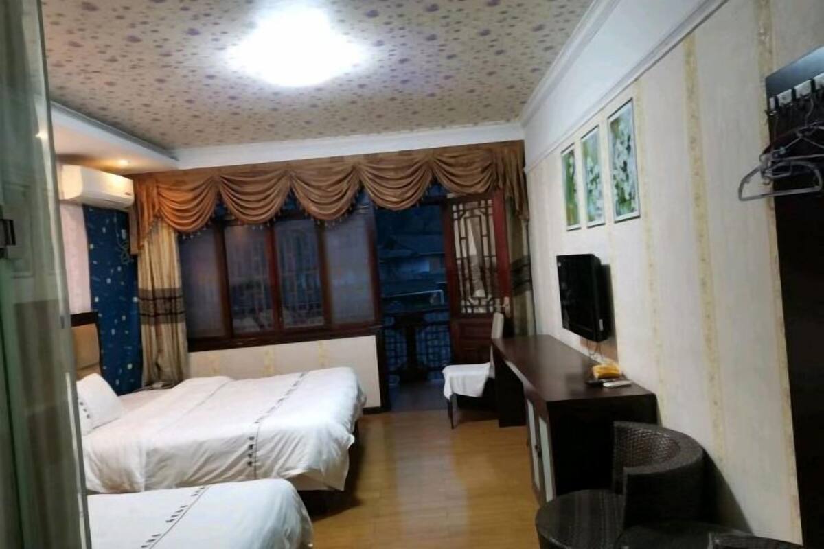 Relax in this traditional room with two single beds, a desk, and a TV, surrounded by a floral ceiling and natural light.