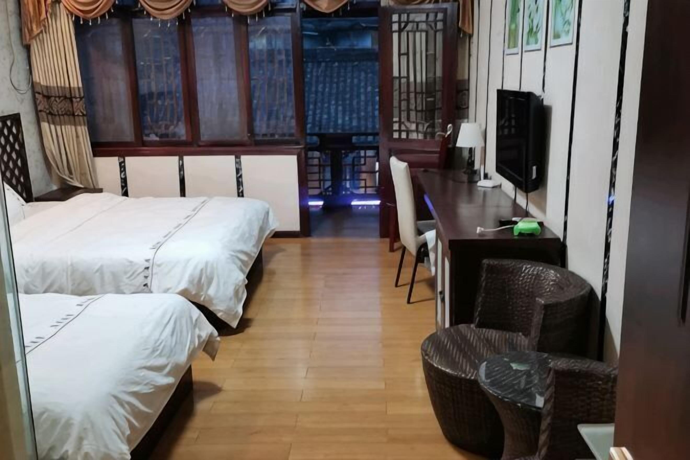A room with two beds, a dining table, chairs, a TV, and a window with curtains.