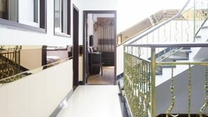 A corridor with a staircase on one side and a door leading to a room with a bed and curtains. - Haiyue Hotel (Ya'an)
