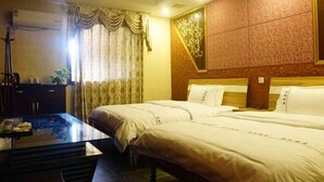 A hotel room with two beds, a wooden headboard, a large mirror, and a desk with a lamp. - Haiyue Hotel (Ya'an)