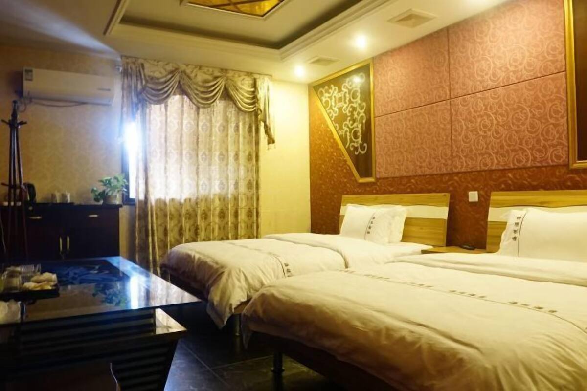A hotel room with two beds, a wooden headboard, a large mirror, and a desk with a lamp.