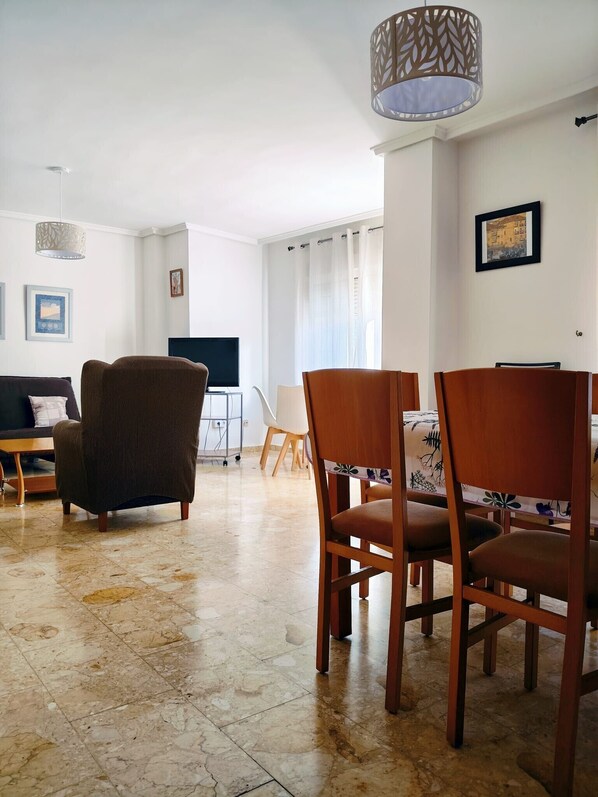 A living room with a sofa, chairs, a TV, and a dining table.