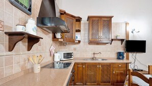 A kitchen with wooden cabinets, a microwave, a coffee maker, and a television. - Vacation Apartment 'Finca La Bonita Ap P1' with Shared Pool, Shared Terrace and Wi-Fi (Arona)