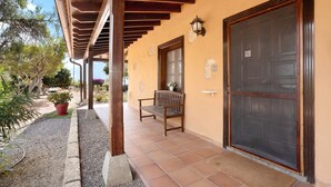 A covered patio with a bench, a door with a security screen, and a potted plant. - Vacation Apartment 'Finca La Bonita Ap P1' with Shared Pool, Shared Terrace and Wi-Fi (Arona)